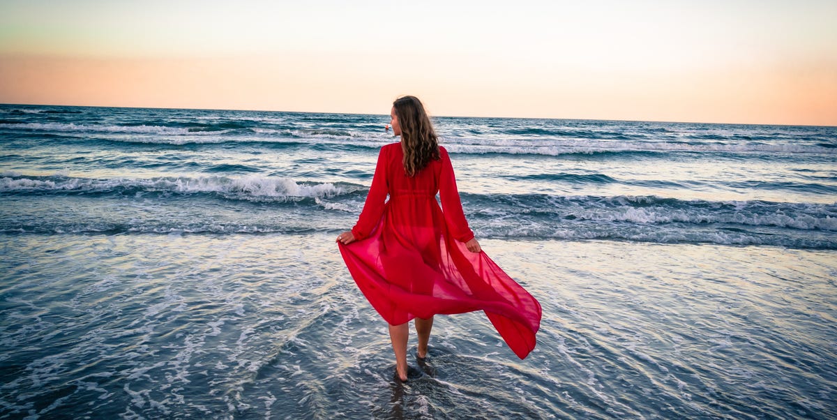 Bikini Essence Sales Store -Bikini Essence Sales Store rear view of woman wearing red dress walking on royalty free image 1652389795